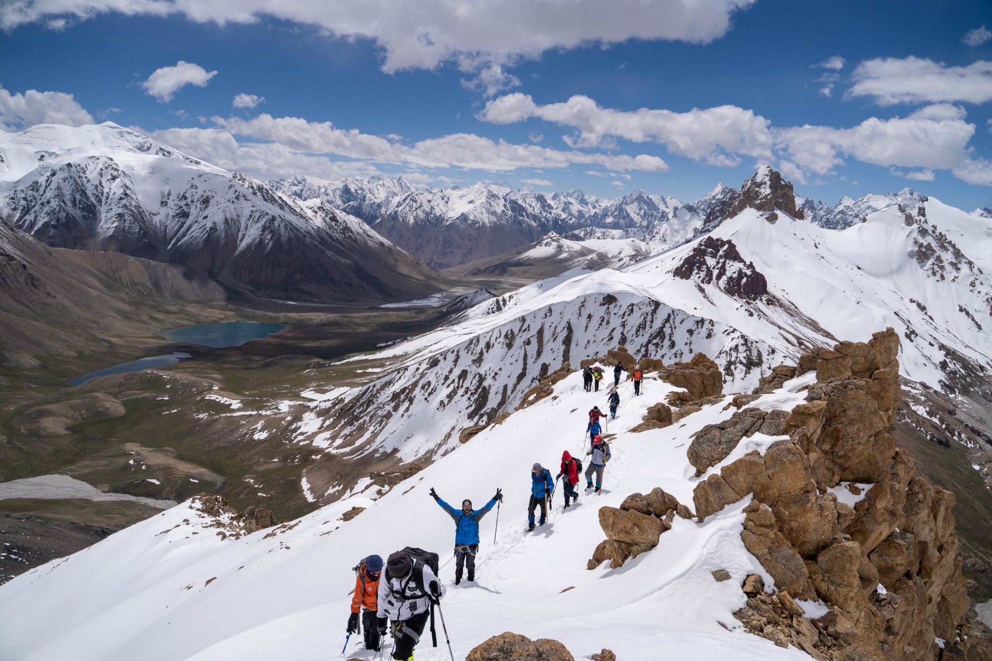 Climbers on a ridge in the Karakoram with turquoise lakes below